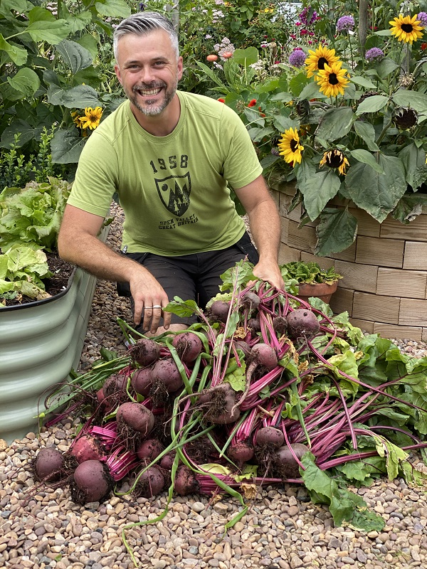Dobies new vegetable seed range 2023 includes this new beetroot 'Jolie' variety pictured with Rob Smith, who kneels behind a large pile of harvested beetroot beside raised vegetable beds