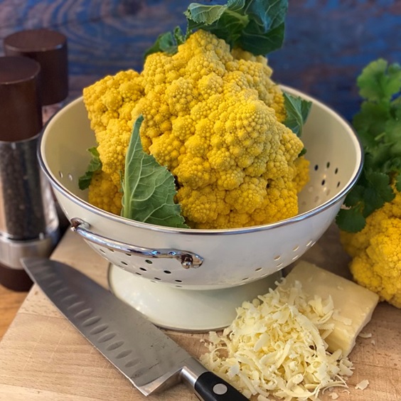 Dobies new vegetable seed range 2023 includes this new yellow-coloured cauliflower 'Amo 125' F1 variety pictured harvested and in a white calendar on a wooden chopping board